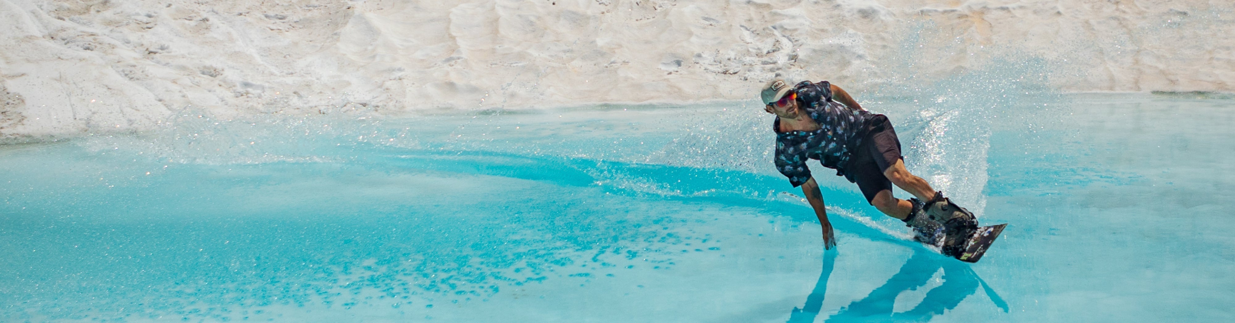A man wearing a melin hat wakeboarding on a lake